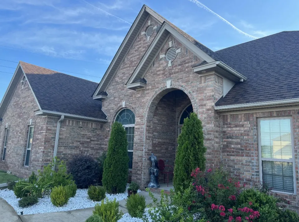 Residential home exterior featuring brick façade, new roofing and manicured landscaping by Landon Roofing in Central Arkansas