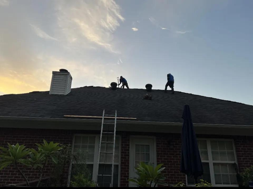 Roofing crew working on a home at sunset