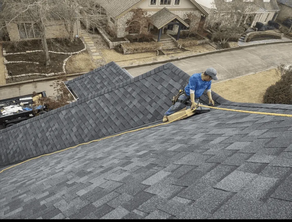 Roofer laying architectural shingles on a steep roof