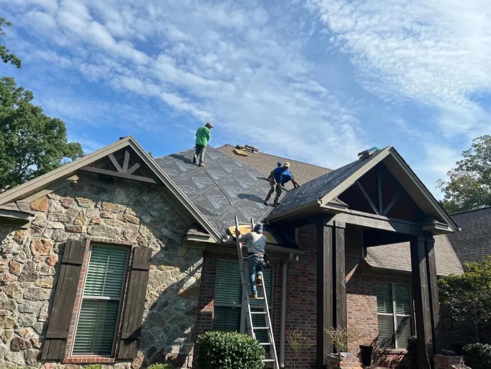 Crew finishing a roof on a stone craftsman-style home